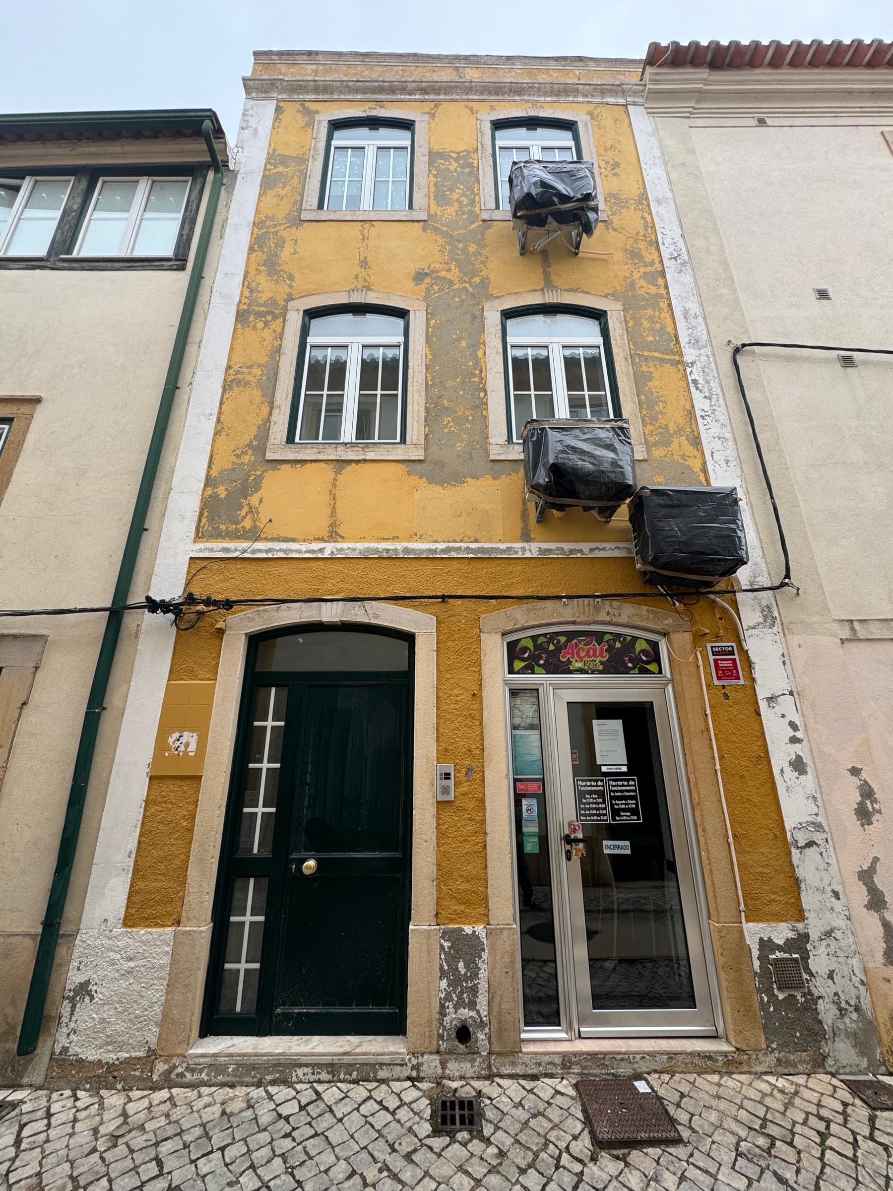 Fachada do edifício em Tomar antes da reabilitação, com pintura degradada e a descascar.