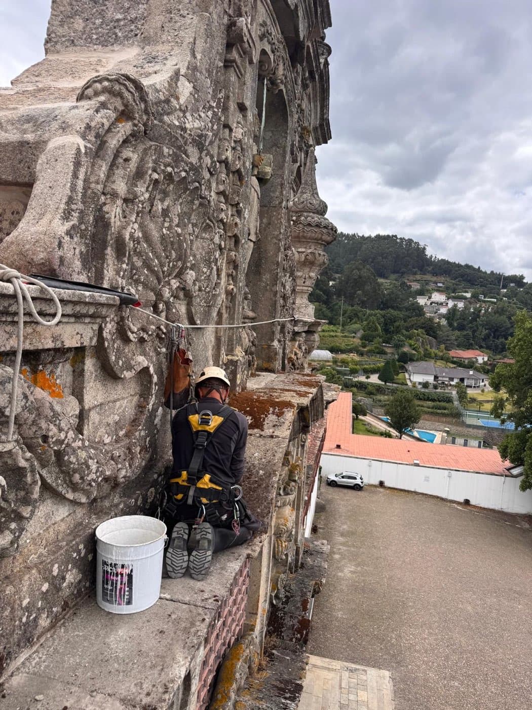 Técnico suspenso em corda a intervir na cornija de cantaria da igreja histórica, em Guimarães.